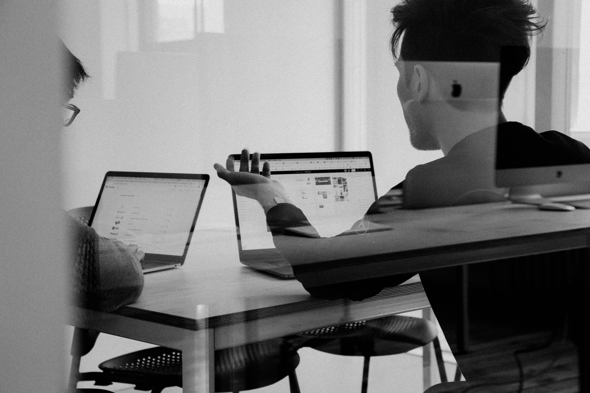 Two professionals discussing Zoho implementation at a desk with laptops